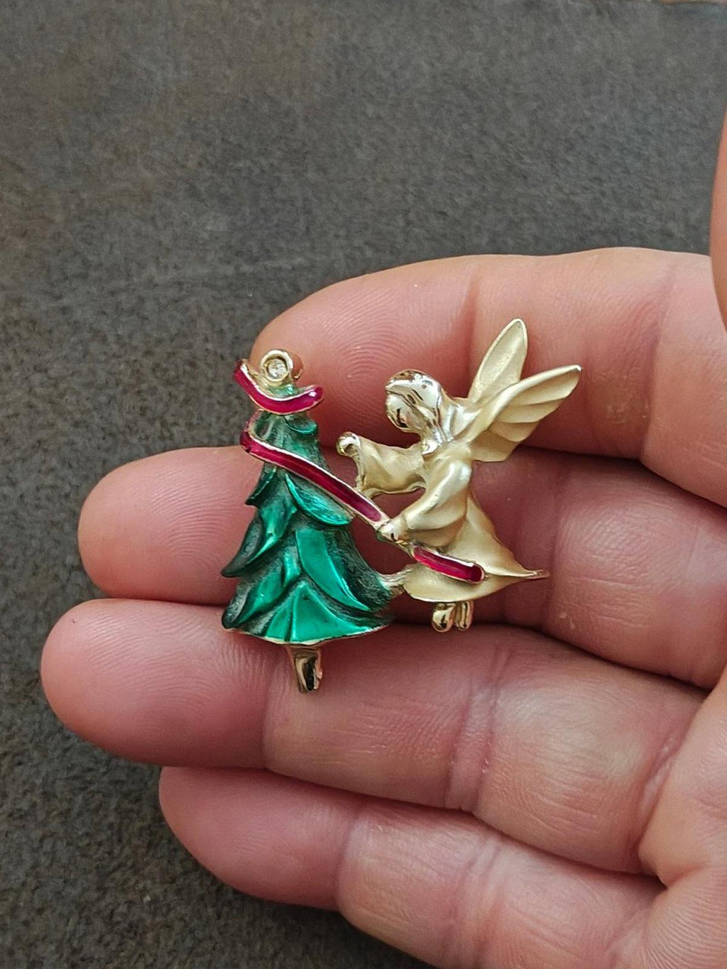 Enamel angel and Christmas tree brooch pin held in hand, gold-tone, green and red enamel