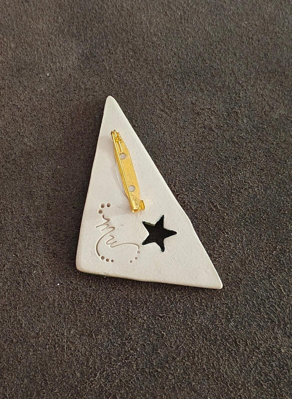 White ceramic triangular pin back with gold clasp and black star