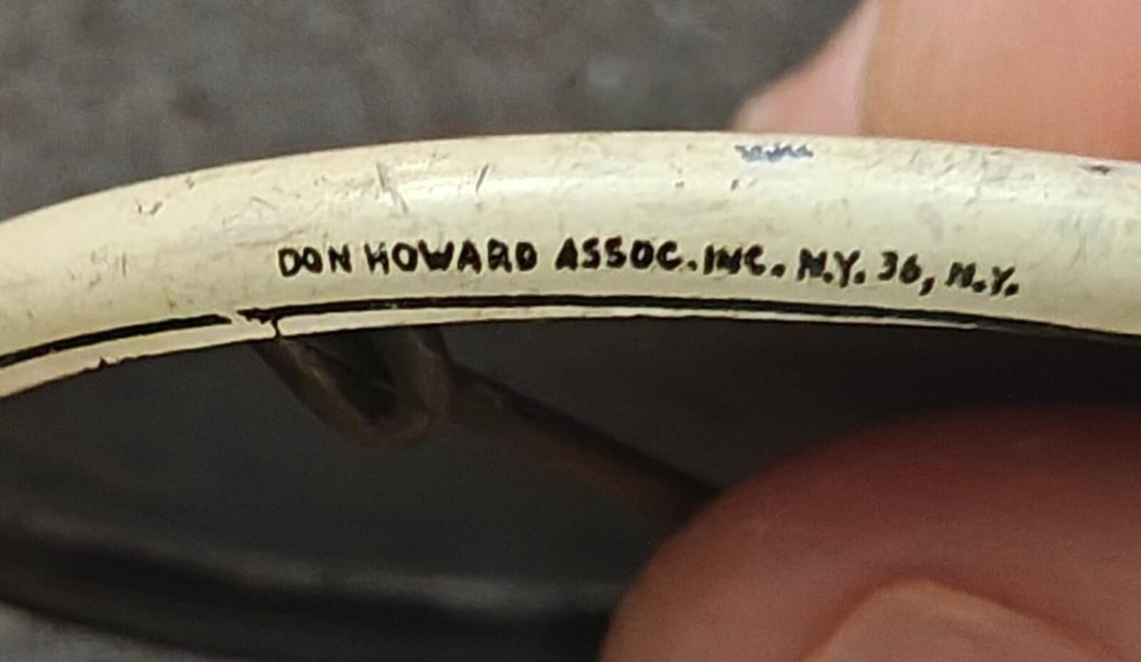 Back of button pin with stamped text "DON HOWARD ASSOC. INC." and NY address