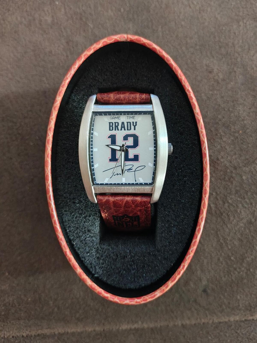 Square face Tom Brady game-time watch with brown leather strap and silver case.