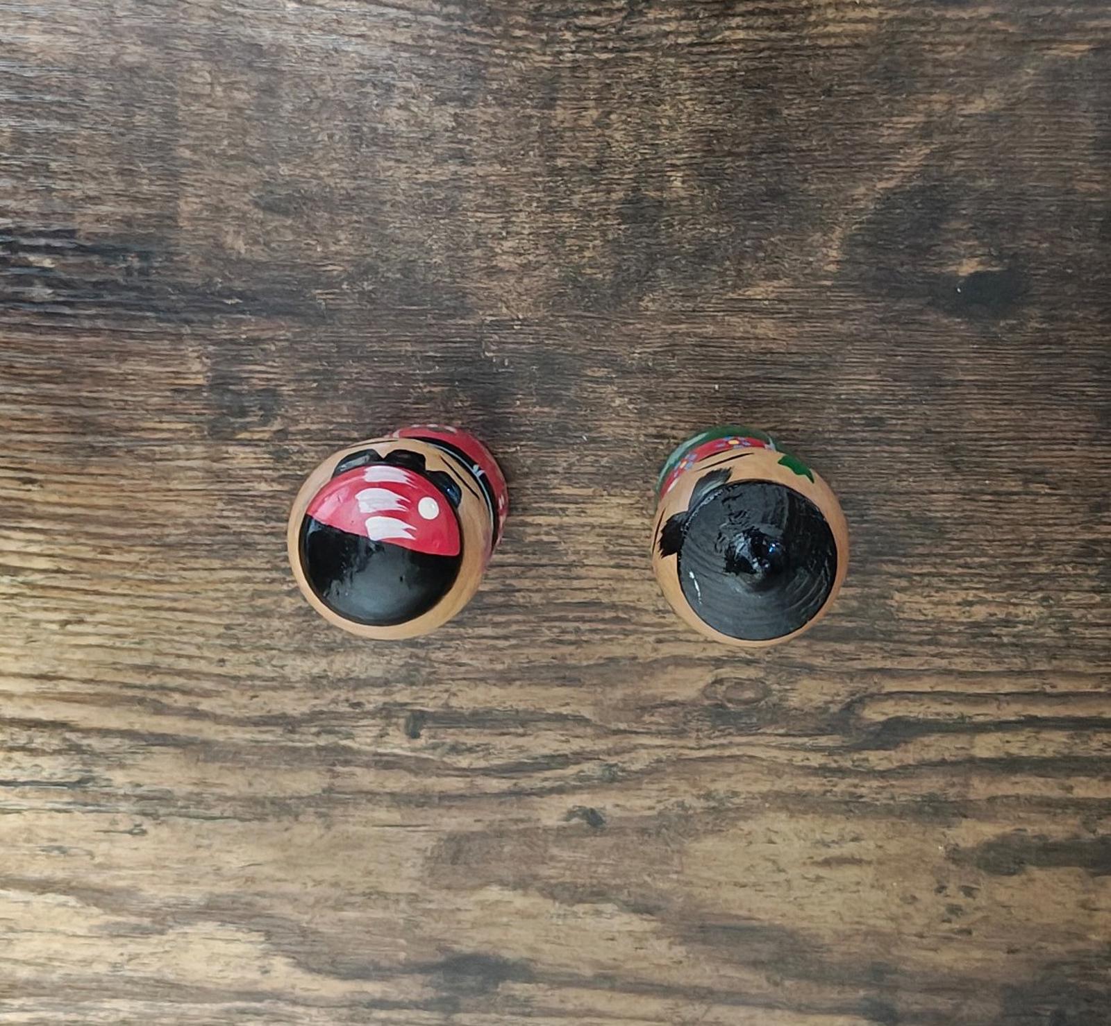 Close-up of the bottoms of two Japanese kokeshi wooden dolls on a wooden surface