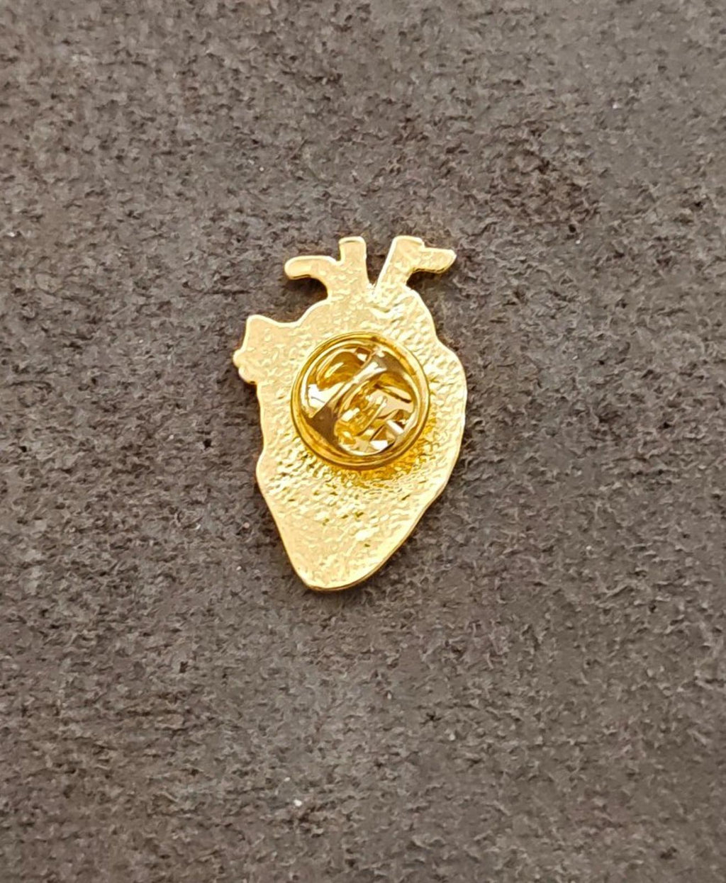 Gold-tone anatomical heart enamel pin back with round clasp detail, plain gold finish