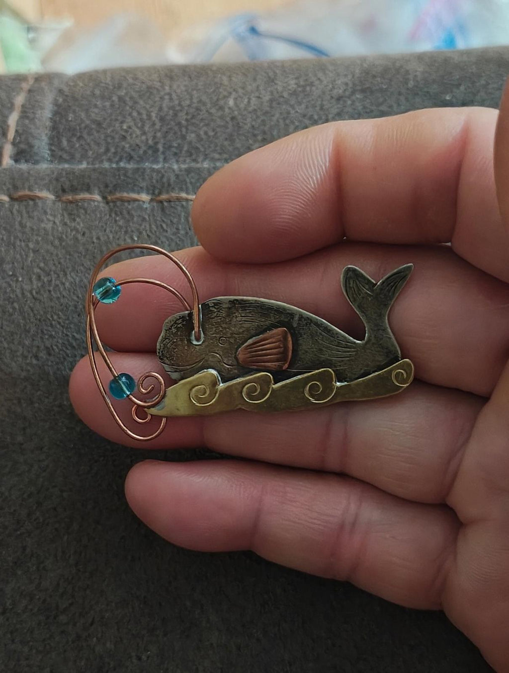 Gold-tone whale brooch pin with full front view, blue stones, copper wire loop, dark green whale
