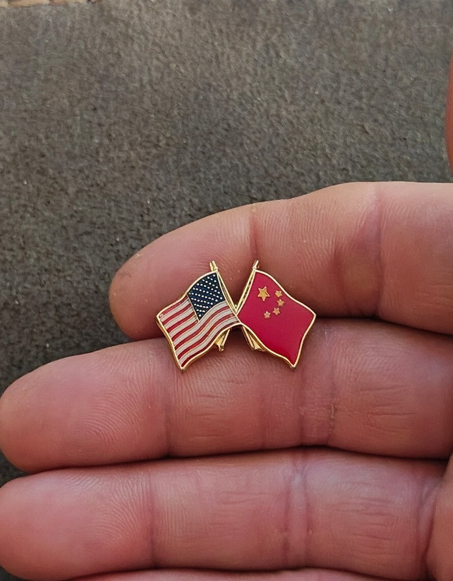 Gold tone enamel lapel pin with crossed US and pink China flags held in fingers.