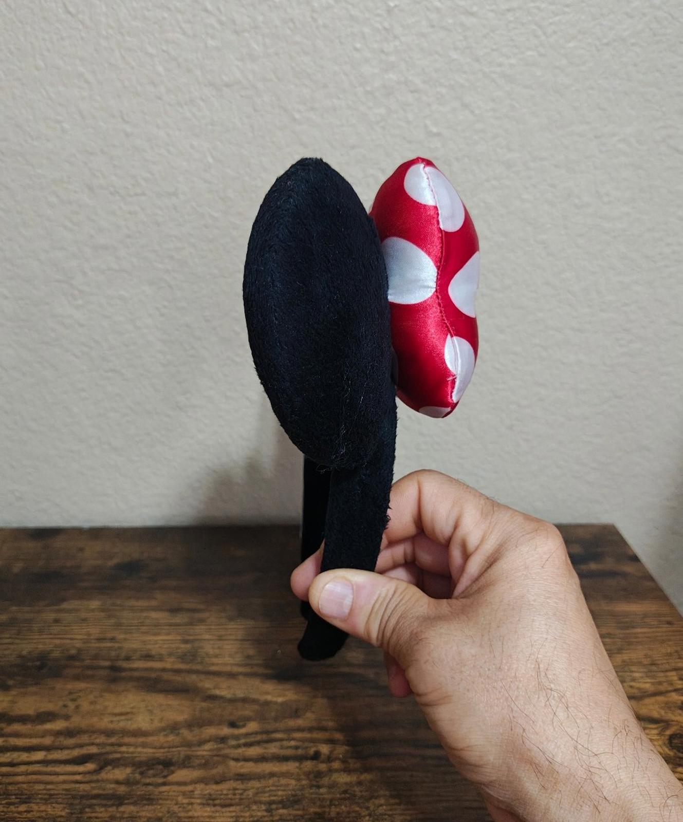 Side-facing red and white polka-dot bow ear headband with black fabric ears
