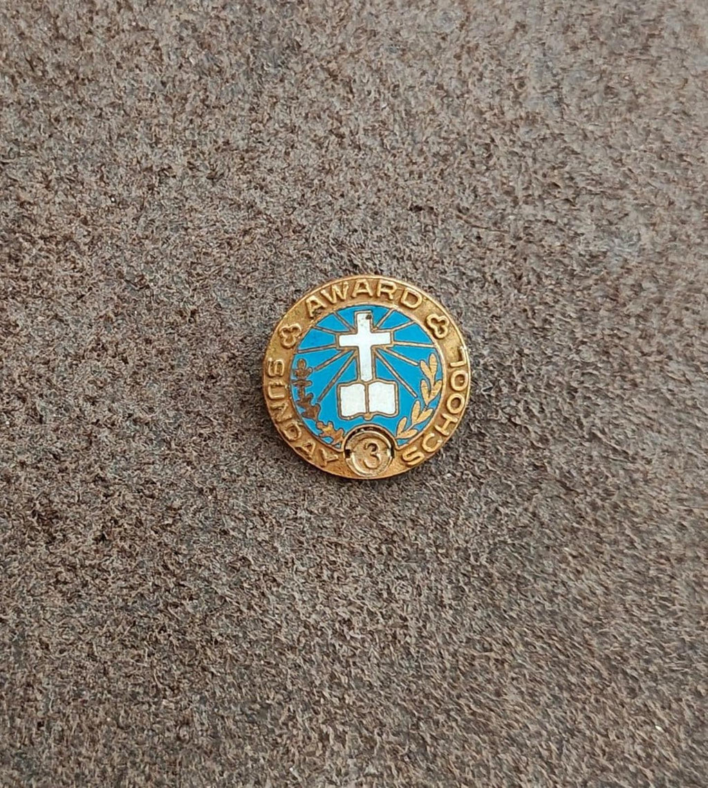 Vintage gold-tone award pin with blue enamel cross, laurel, and "SCHOOL" text around ring