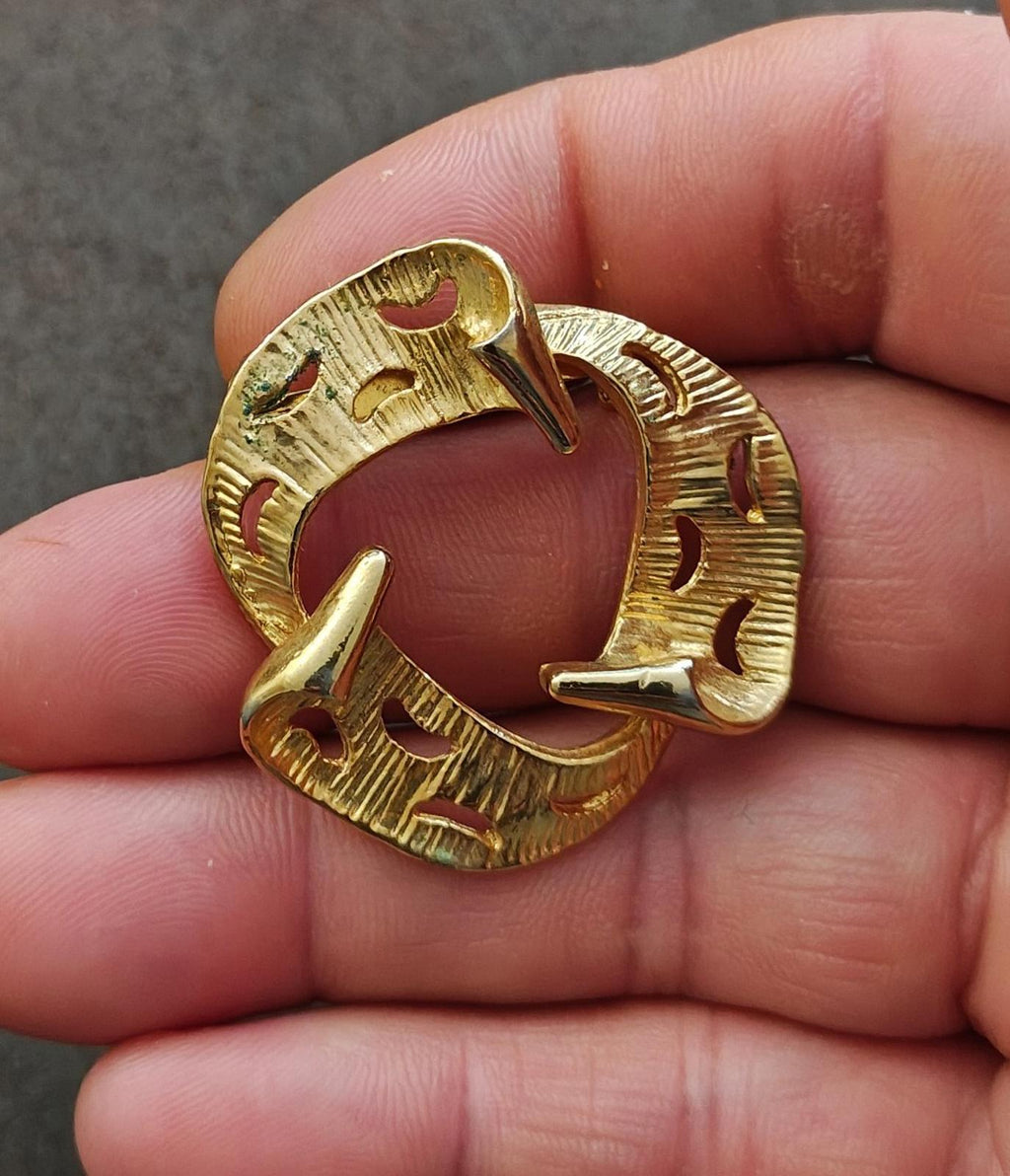 Gold tone circular abstract brooch close-up front with curved textured arcs