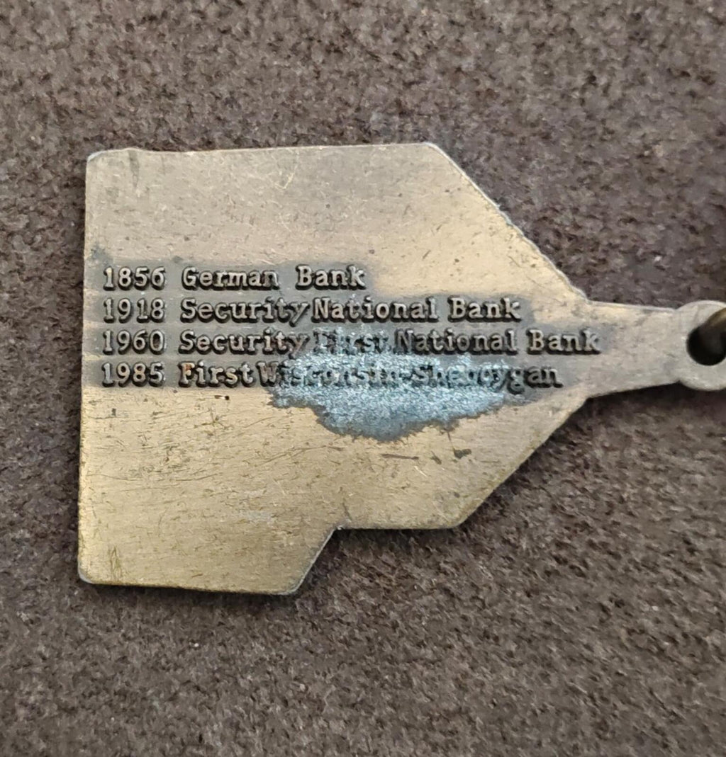 Metal keychain tag with engraved bank history text and round key ring
