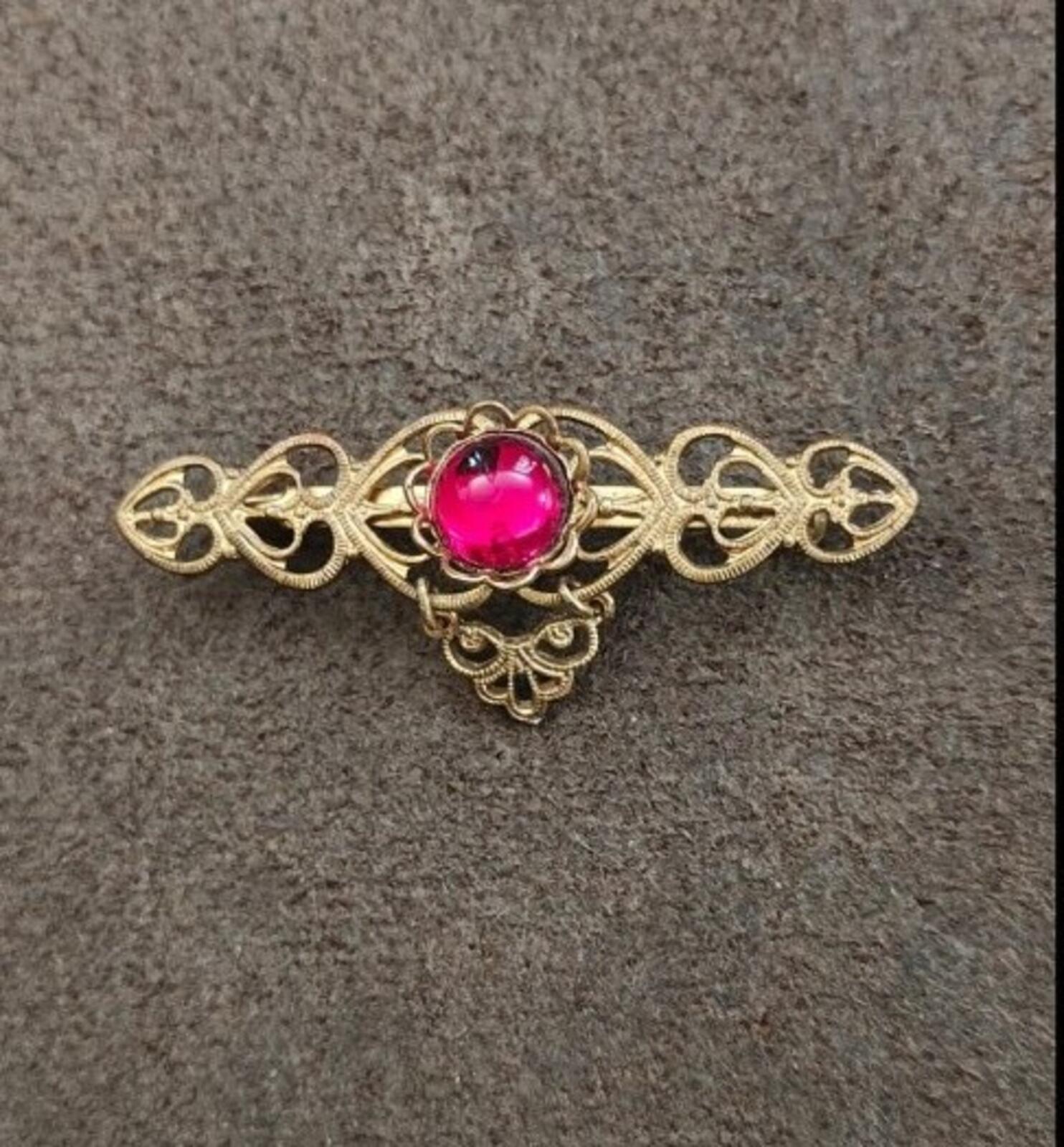Gold-tone decorative heart brooch pin with center red cabochon and open hearts