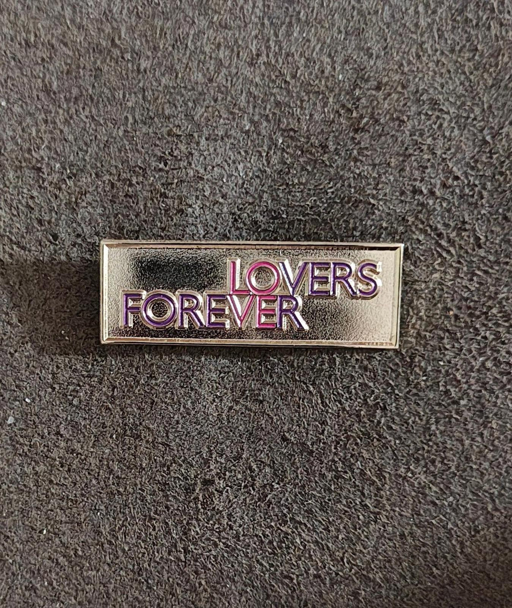 Gold-tone “Lovers Forever” enamel pin, front view with “LOVERS” above “FOREVER” lettering.