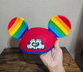 Red felt Mickey Mouse ear hat with rainbow-striped ears and heart-love graphic