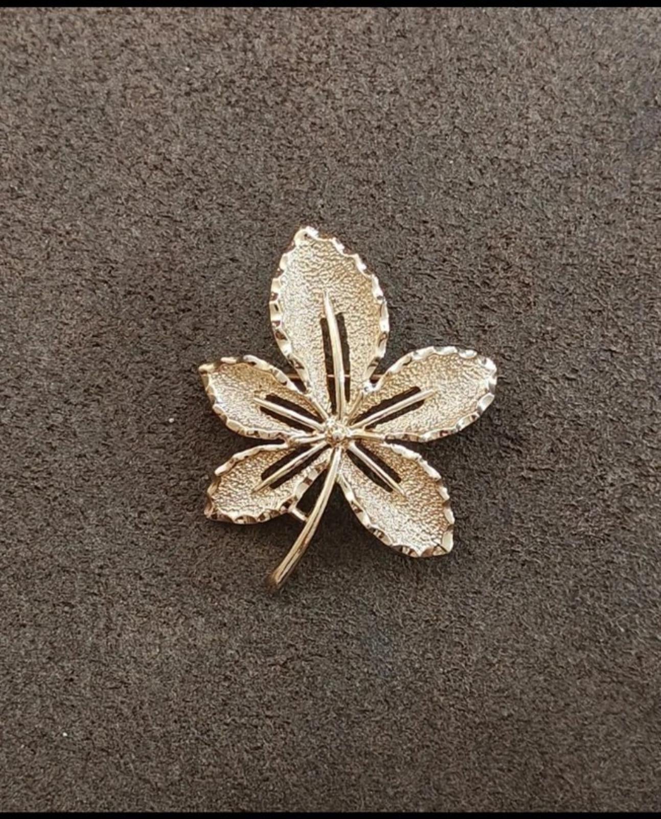 Gold-tone five-petal leaf brooch, angled view showing central textured lines