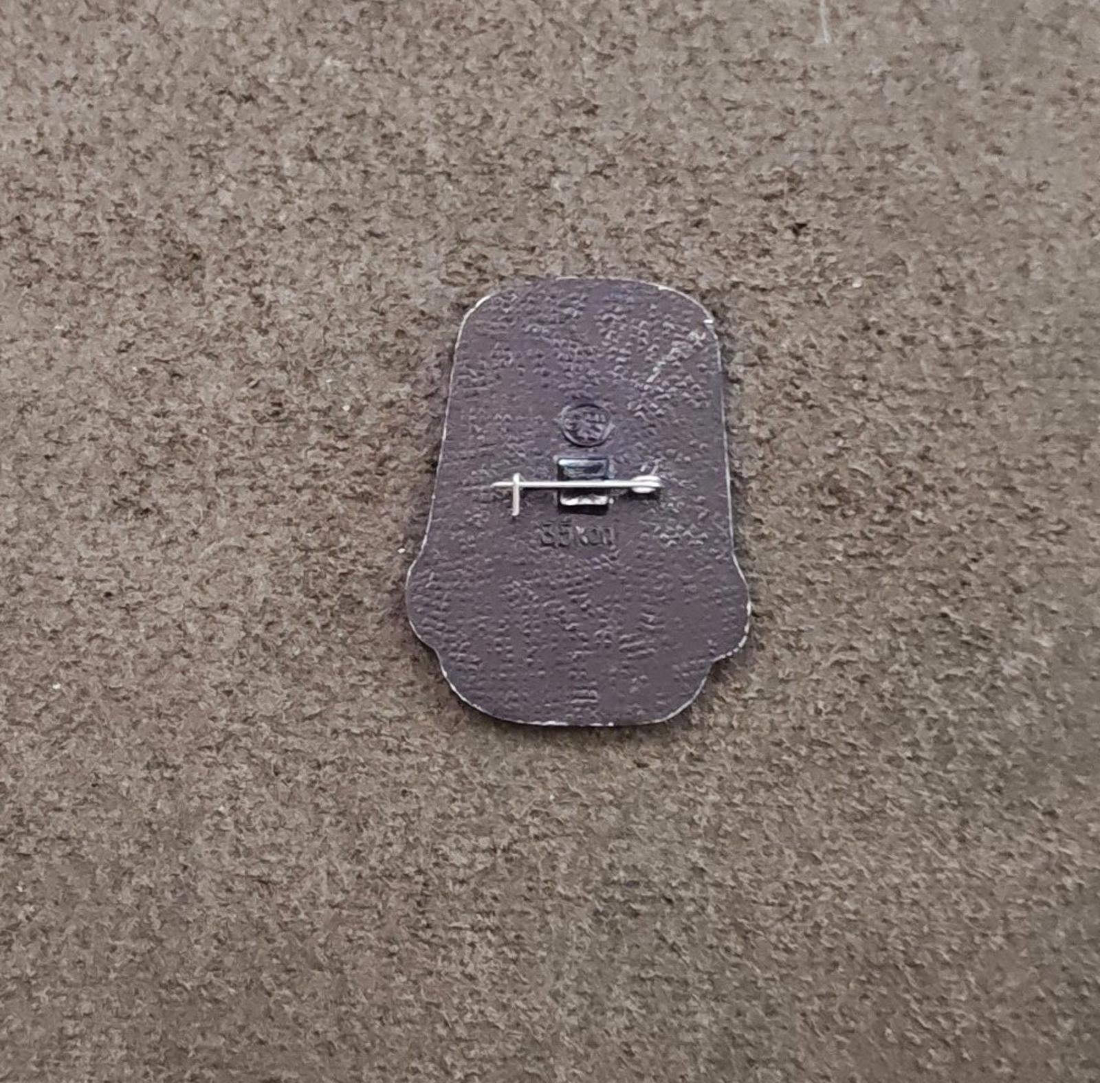 Silver back of a children's enamel pin with pin clasp and safety bar