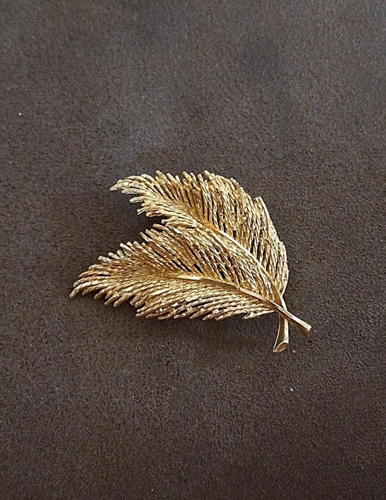 Gold-tone feather and leaf brooch with two layered feathers, shown flat