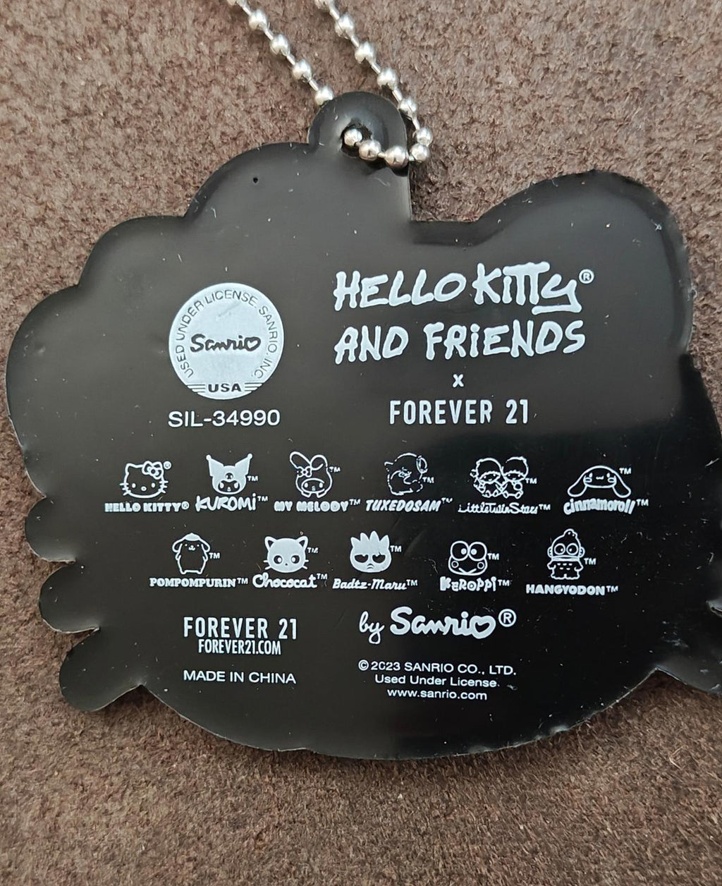 Black rubber Hello Kitty keychain back plate with 'Hello Kitty and Friends' text and icons