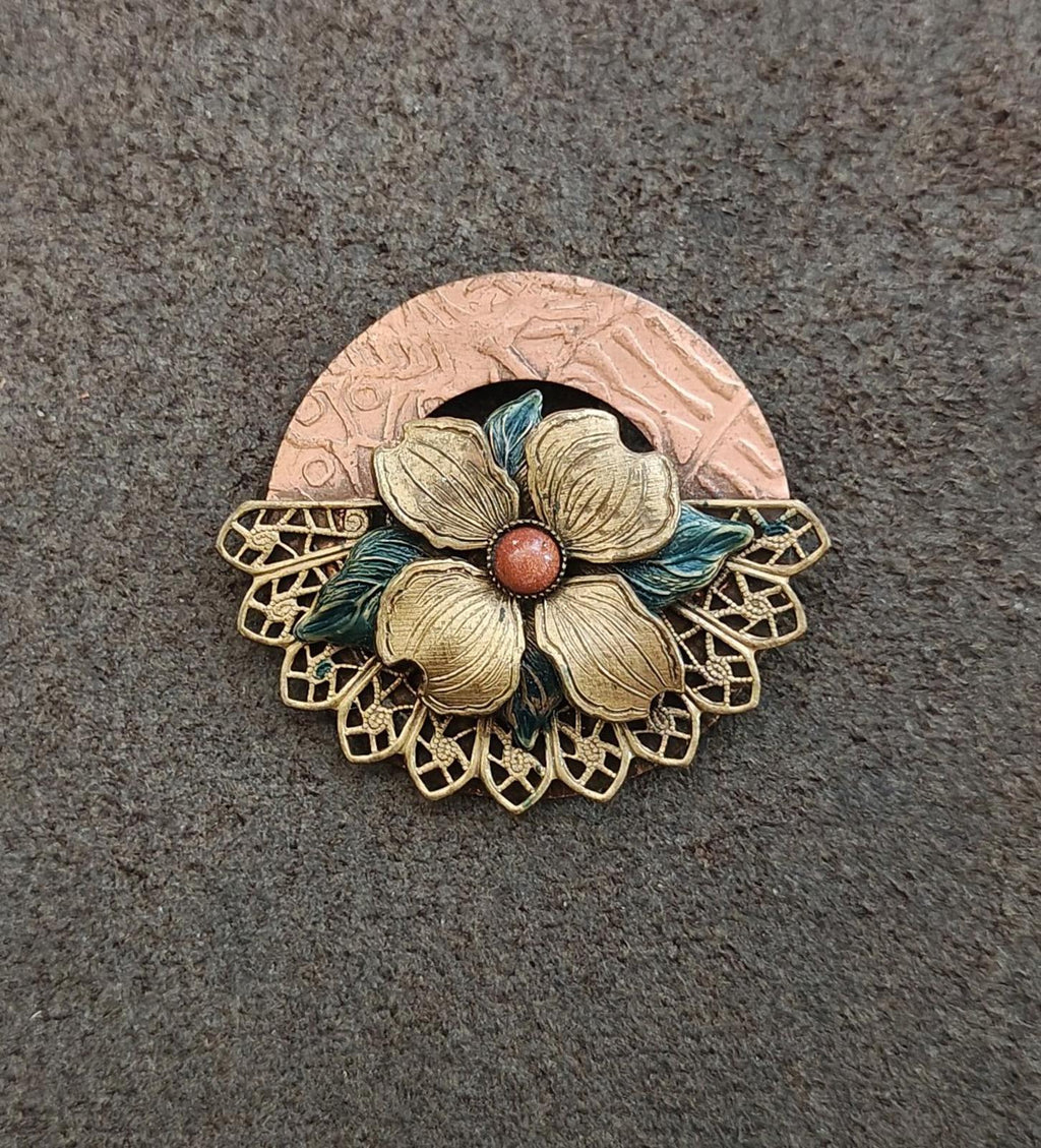 Gold-tone floral enamel brooch with red center bead, blue-green petals, round textured backing