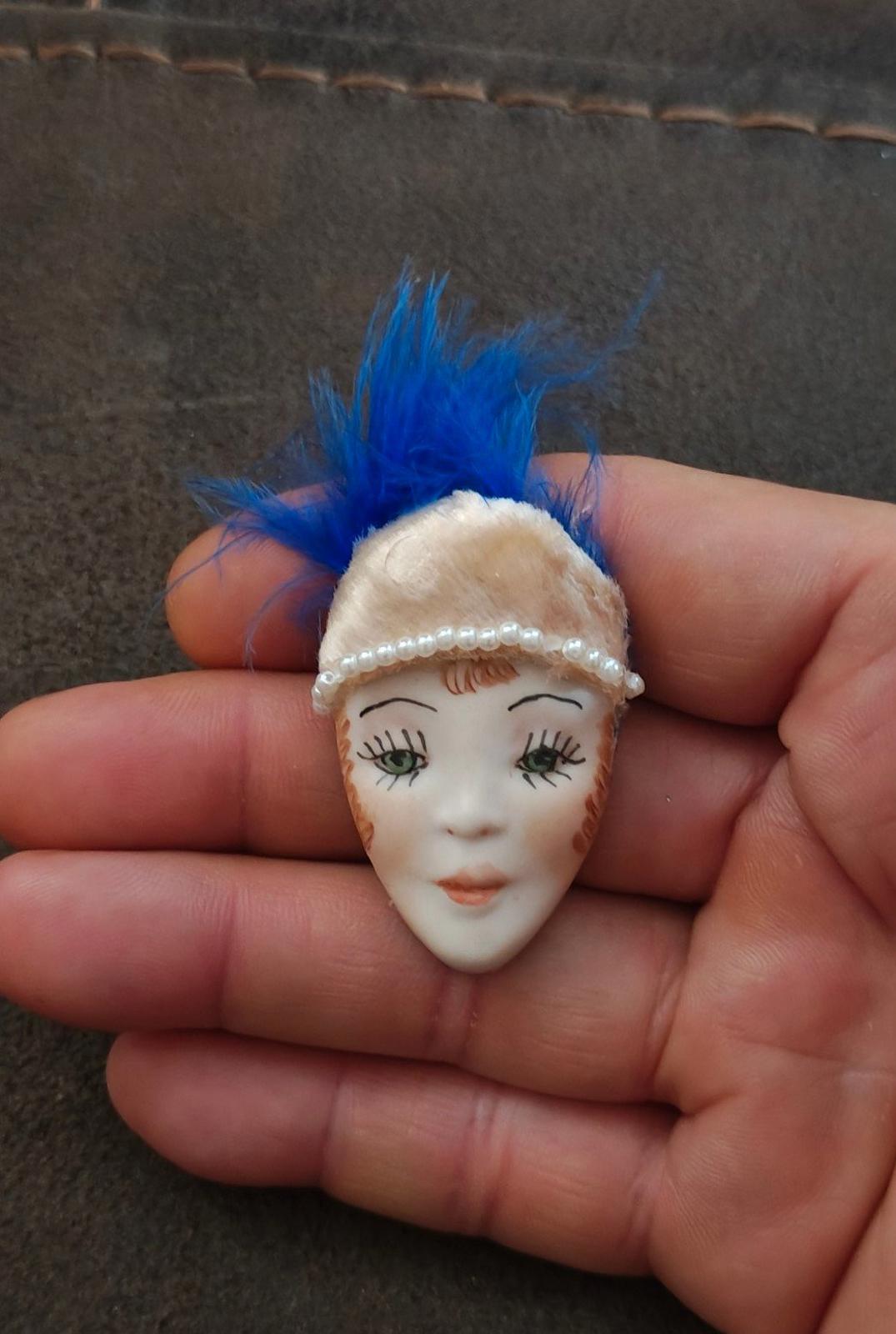 Doll face pin brooch featuring blue feather and cream pearl headband