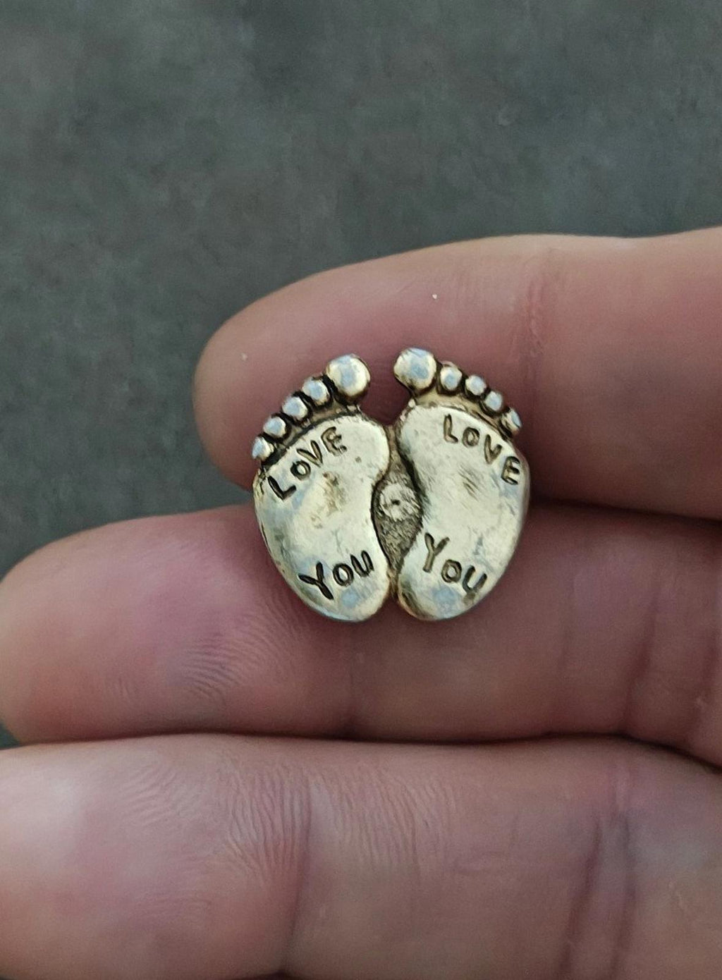 Gold-tone two-footprint brooch pin with "LOVE" and "YOU" on the toes