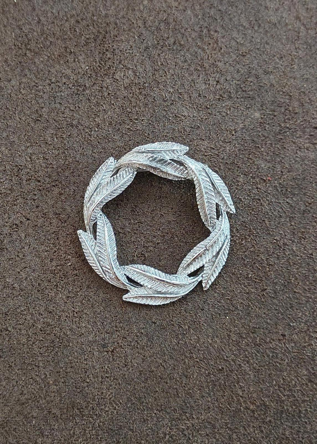 Silver-tone circular leaf textured pin brooch with open frame and curled leaves