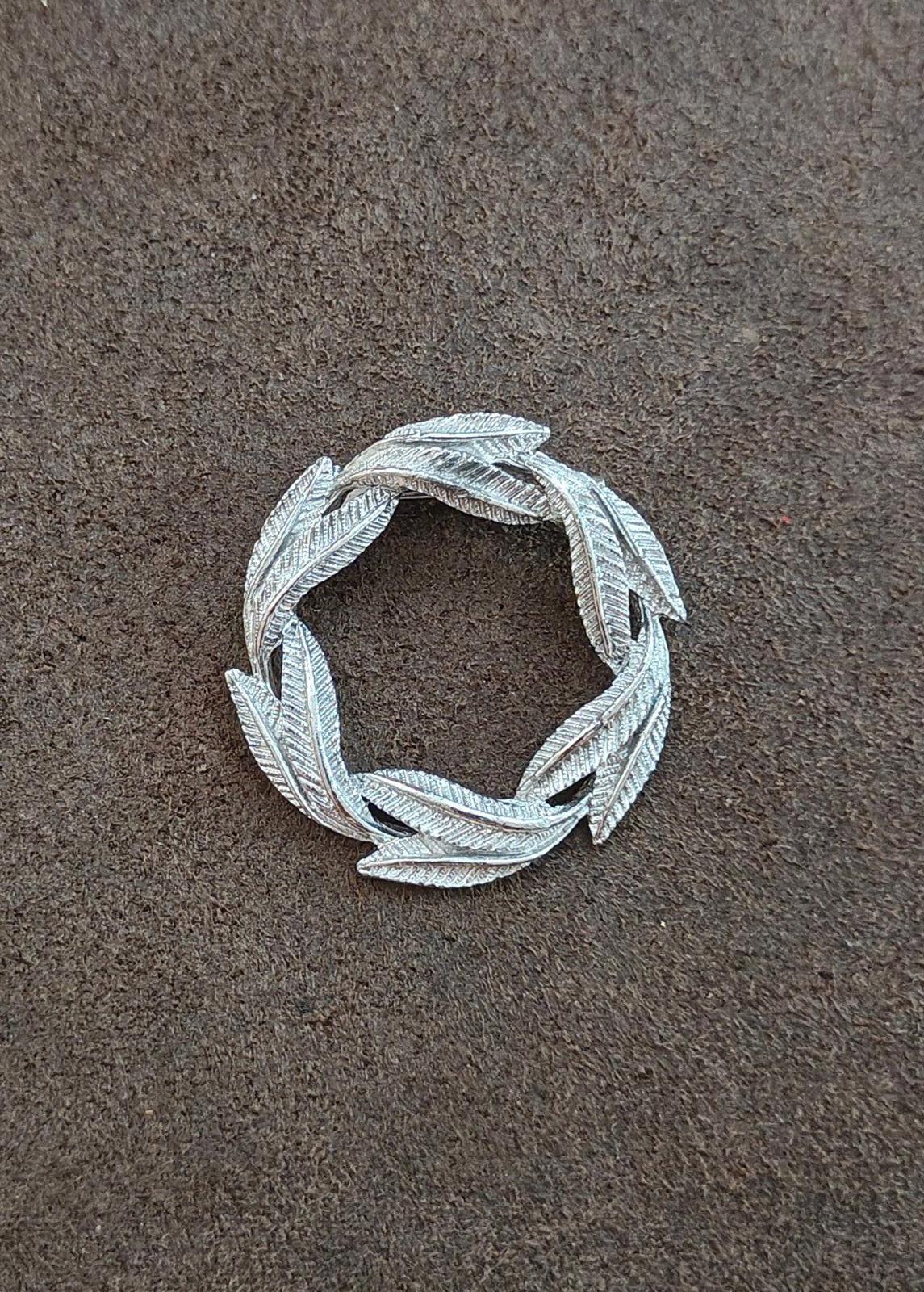 Silver-tone circular leaf textured pin brooch with open frame and curled leaves