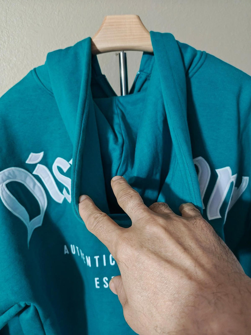 Teal hoodie close-up at neckline with white “Disney” lettering across chest