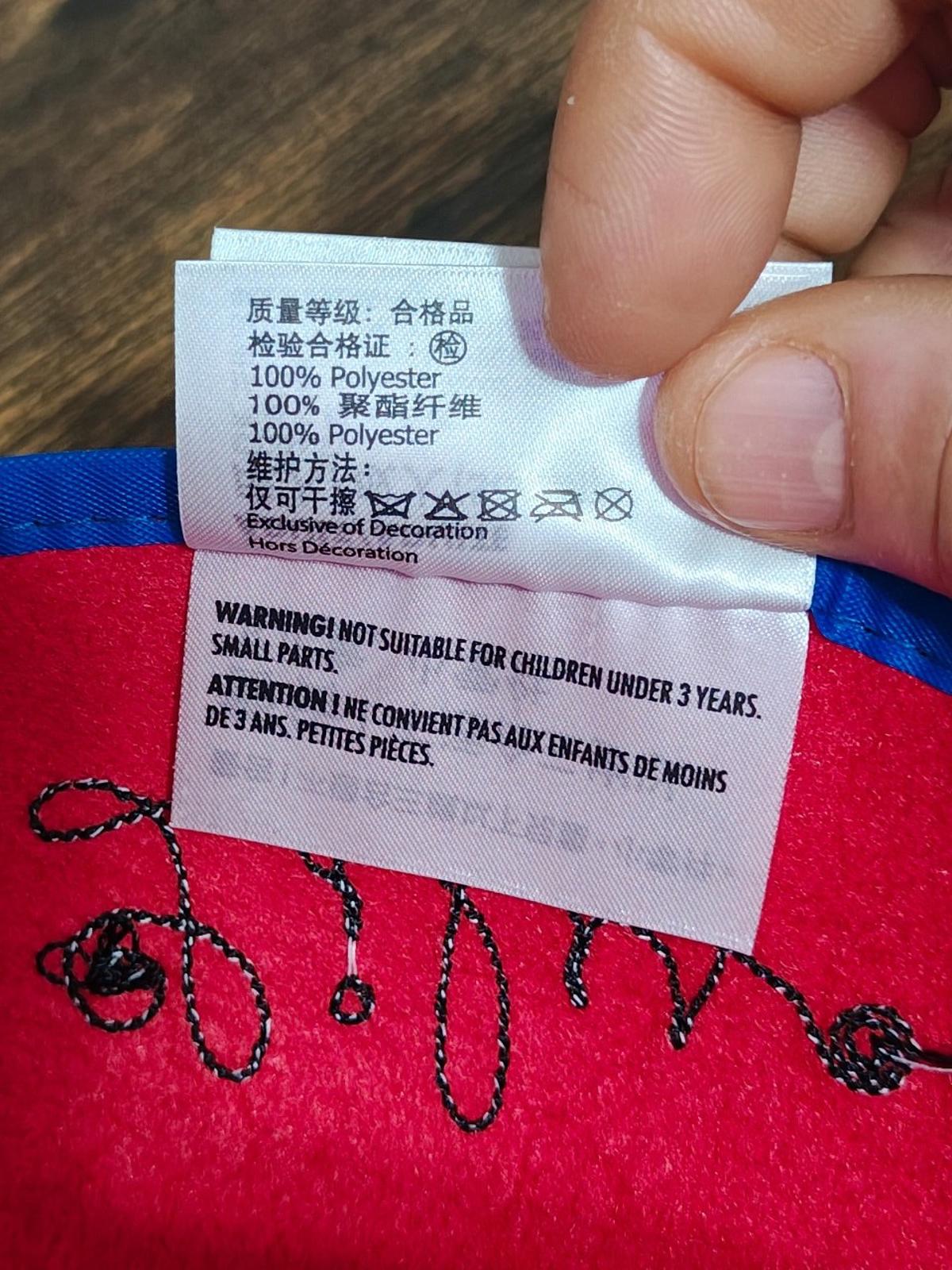 Clothing tag on red felt ear hat showing 100% polyester and care text