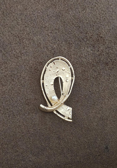 Gold-tone oval abstract brooch pin with faux pearl drop and curved metal frame