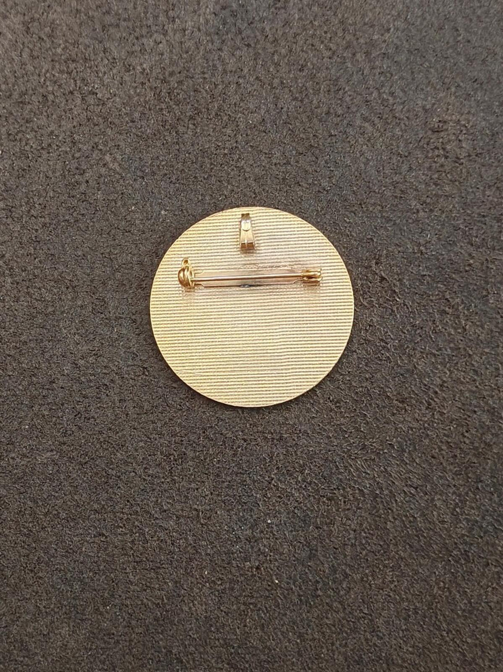 Gold-tone pin back with clasp and safety hinge on round disk.
