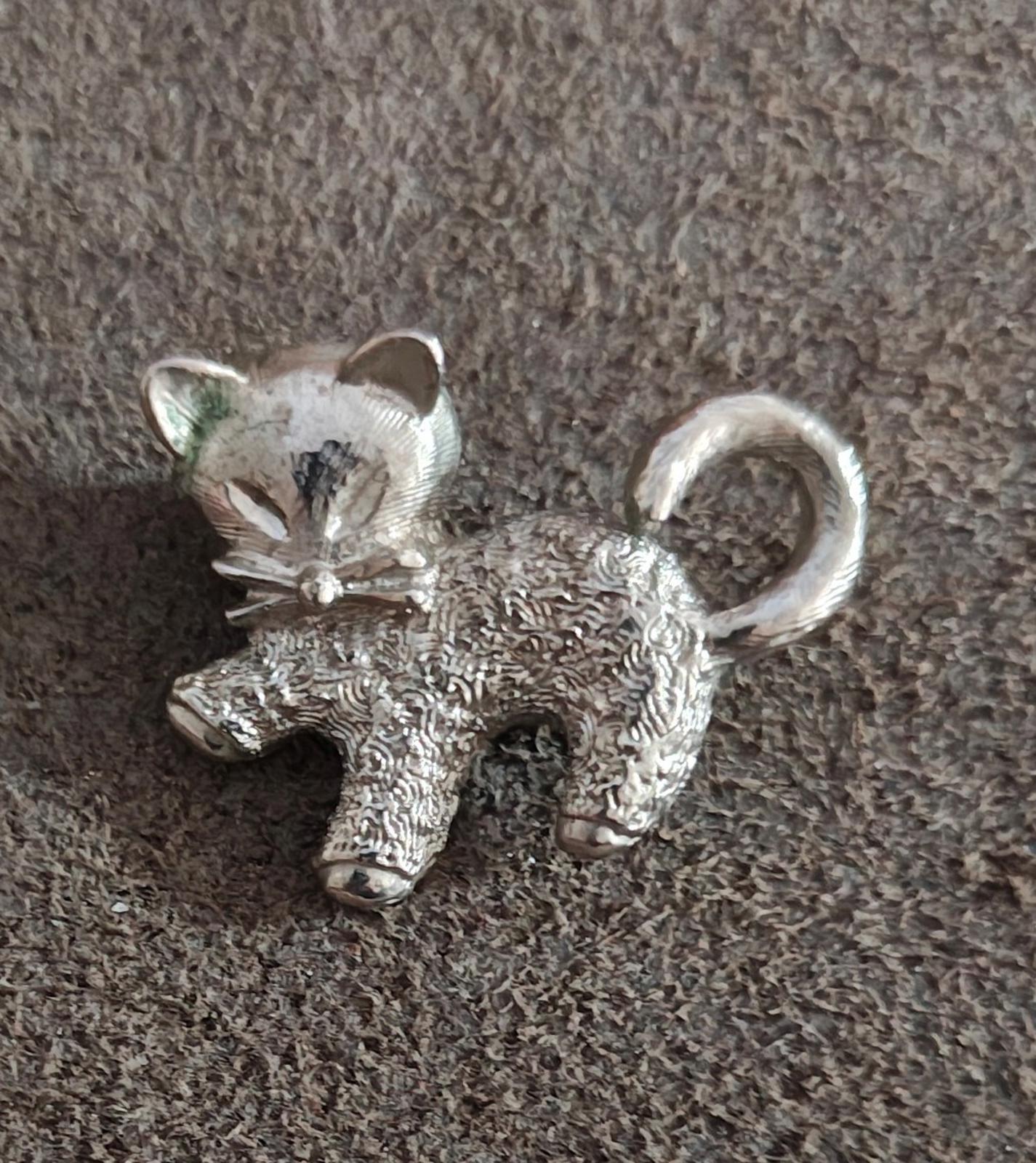 Silver-tone cat brooch pin with detailed textured fur and curled tail.