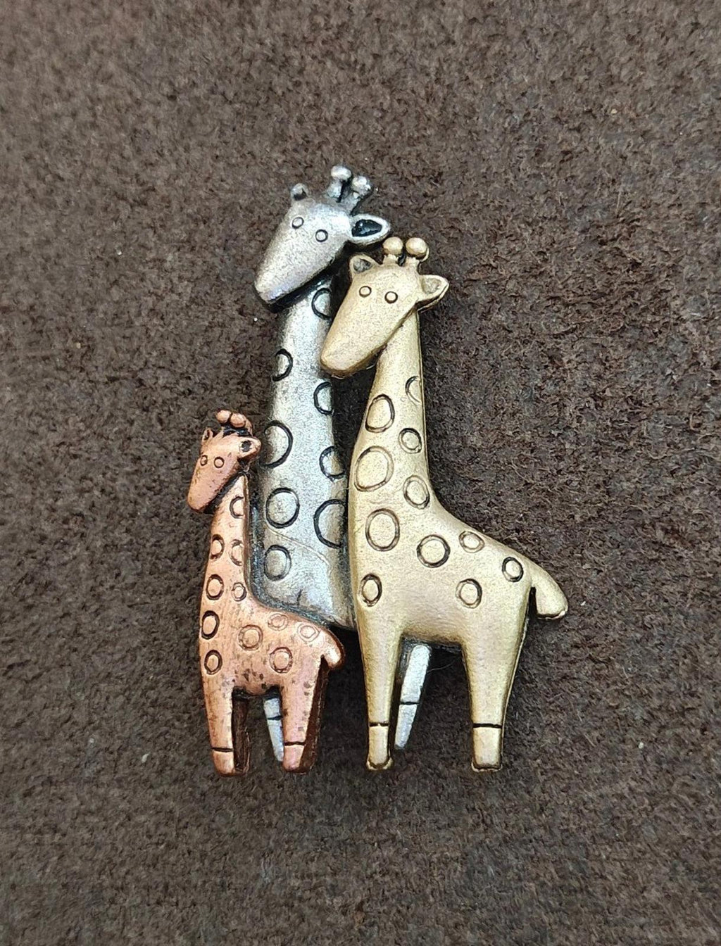 Tricolor giraffe family brooch with three enamel giraffes: pale blue, gold, and copper-brown