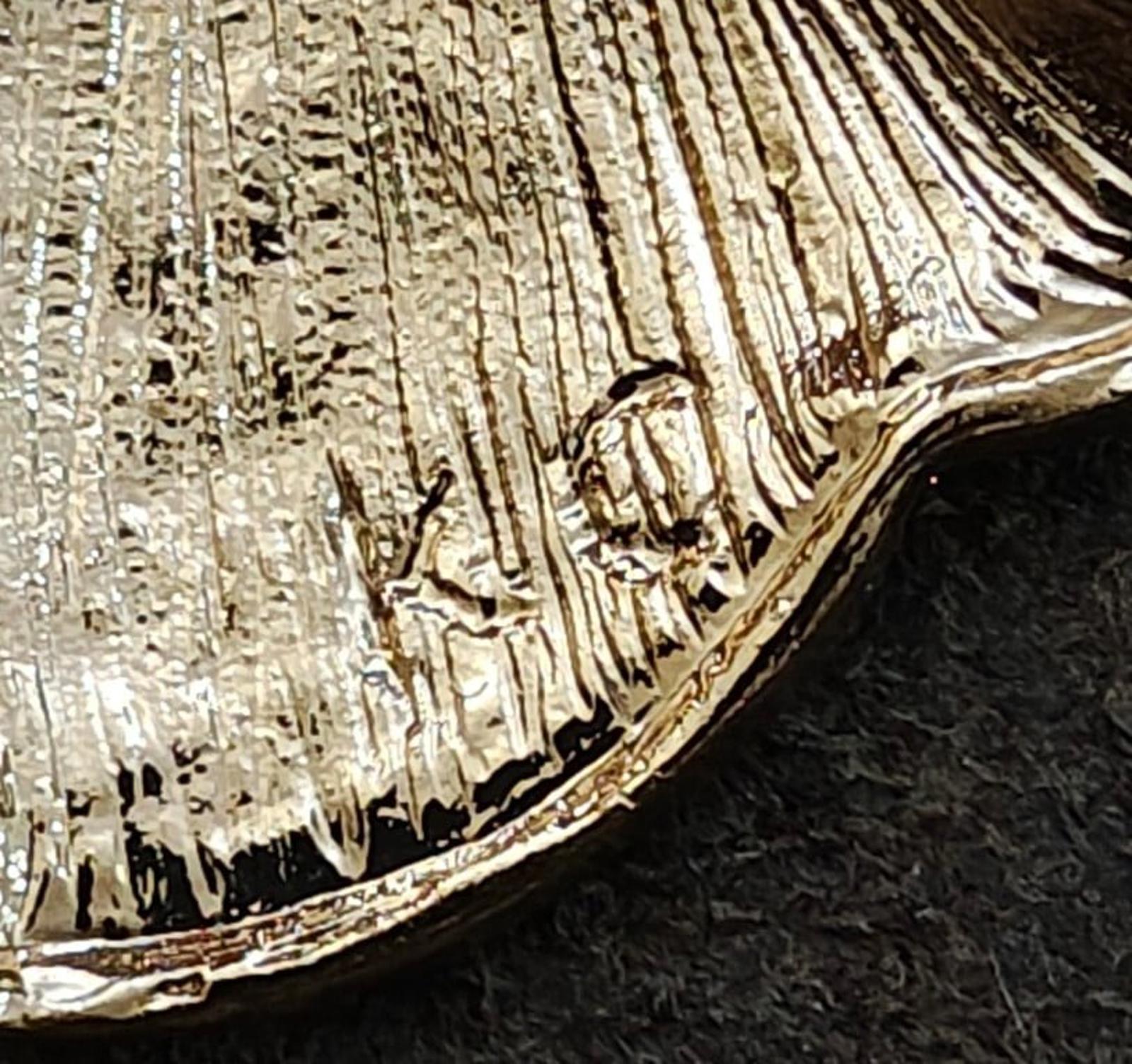 Close-up of gold-tone angel brooch textured enamel surface with raised decorative lines