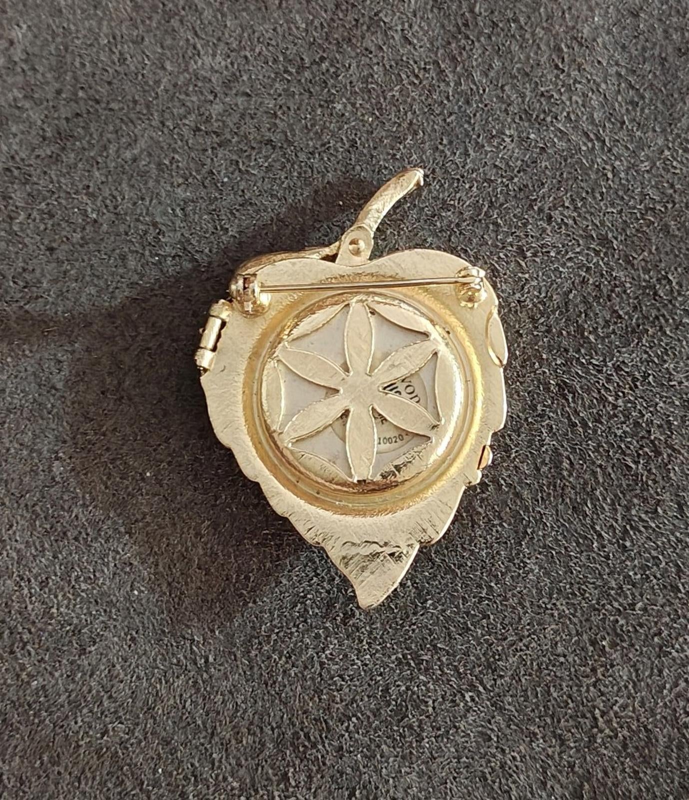 Gold tone leaf locket brooch back view with circular compartment and raised border