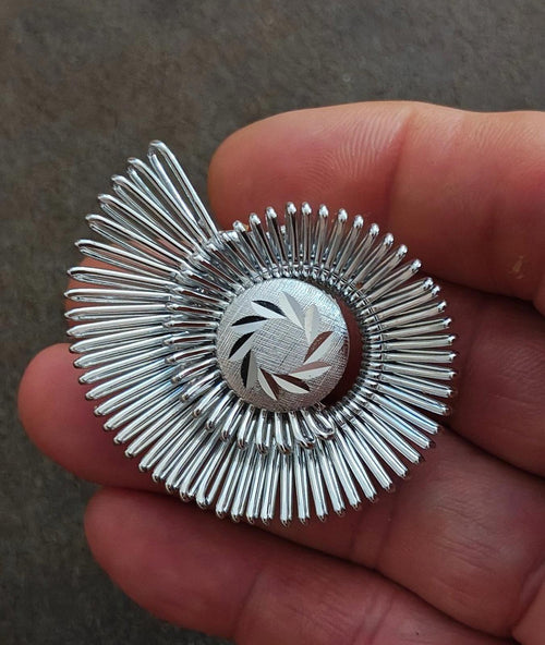 Silver spiral scarf clip with radial prongs and engraved circular center