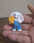 Blue and white plastic Easter bunny pin holding yellow chicks