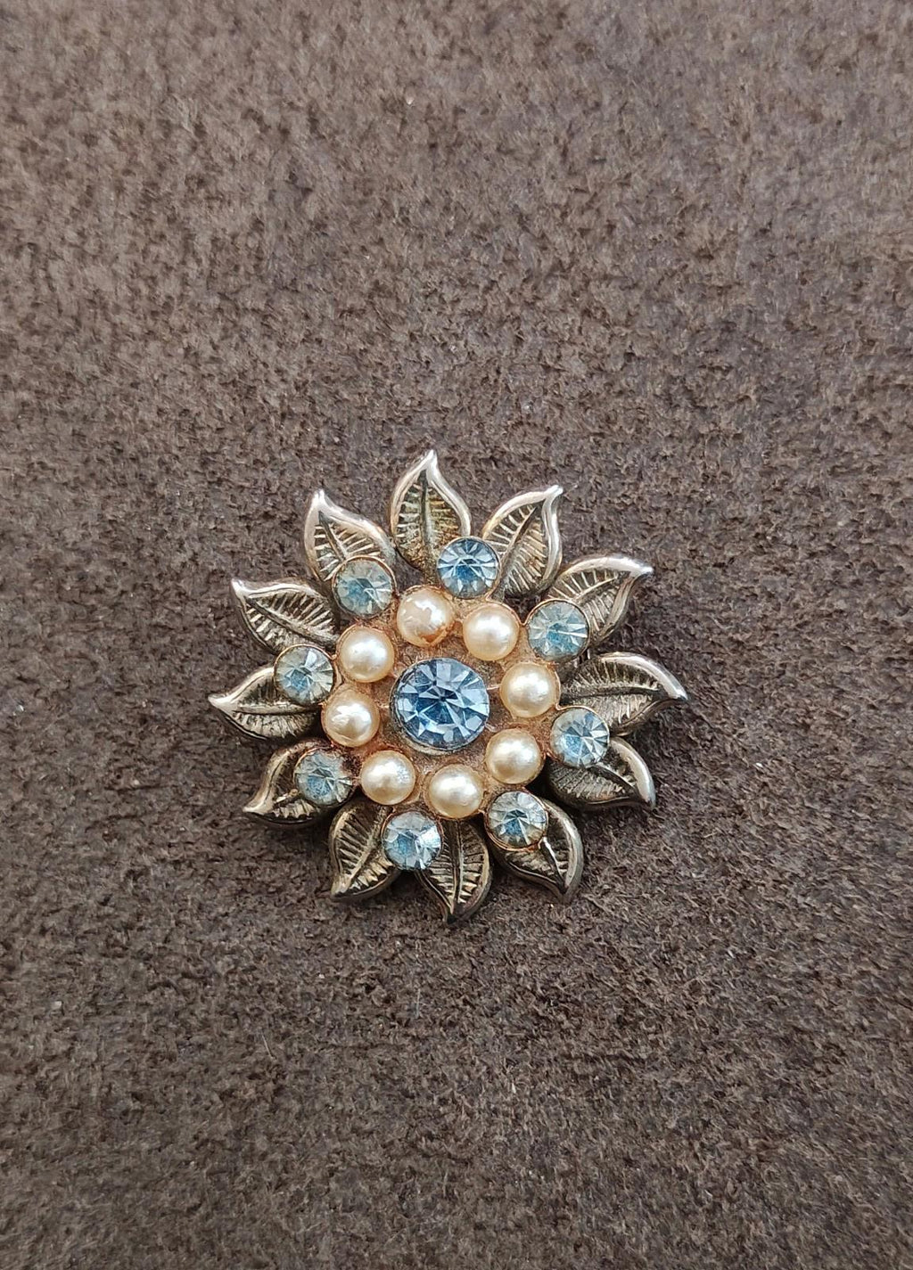 Compact blue rhinestone and faux pearl flower brooch with silver leaf petals.