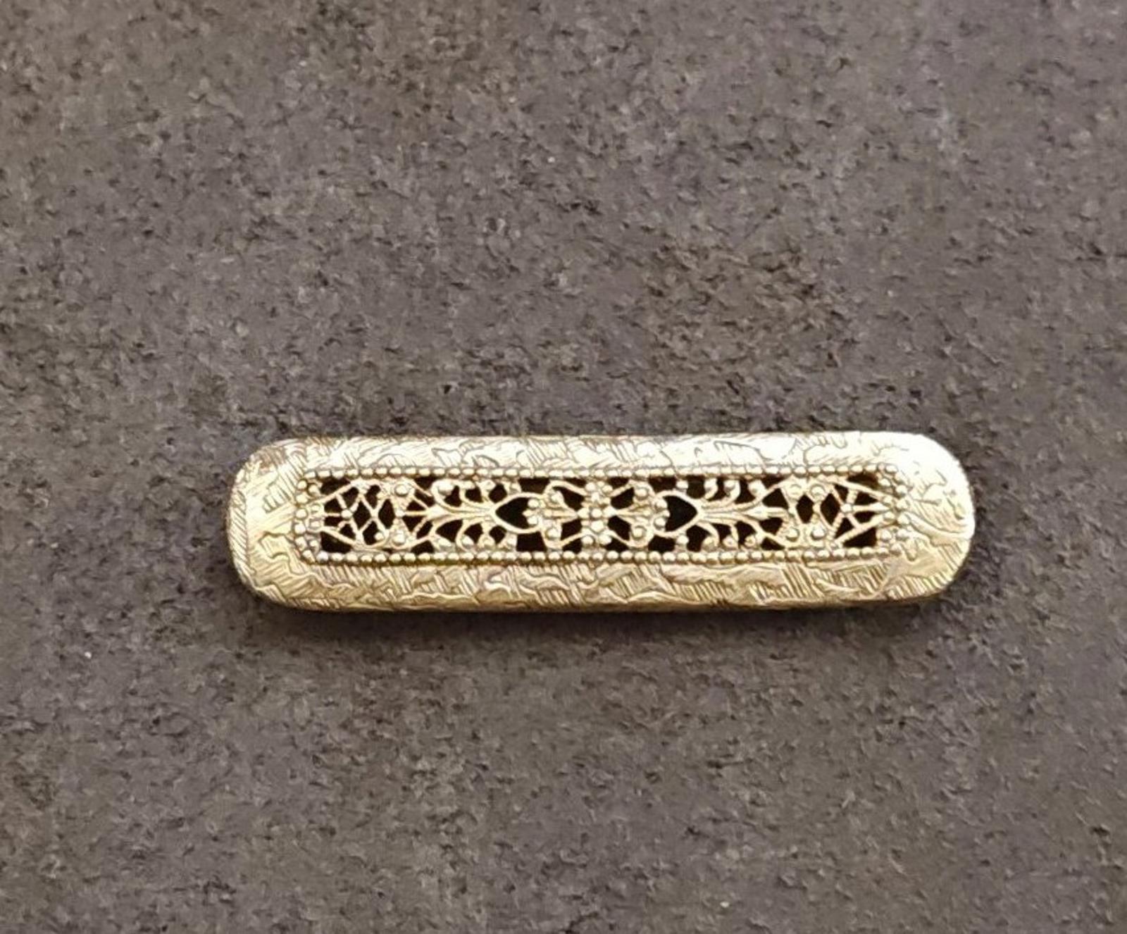 Gold tone Victorian-style filigree bar brooch with intricate scrolling lattice and center design.