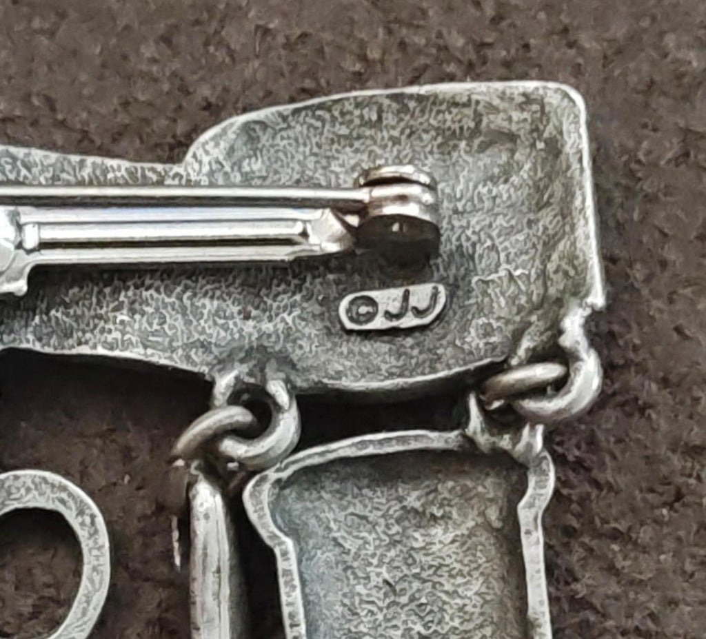 Close-up of silver brooch clasp and hinge with attached charm links