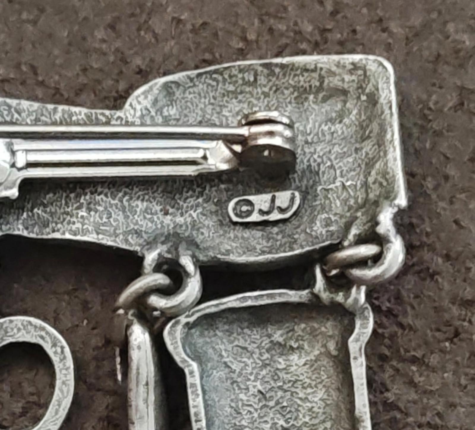 Close-up of silver brooch clasp and hinge with attached charm links