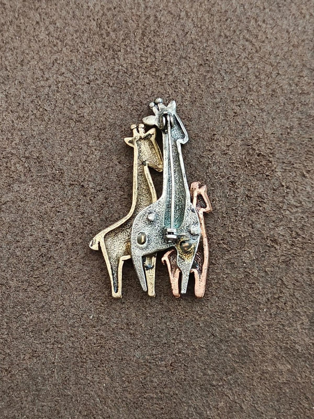 Tricolor giraffe family brooch with four overlapping giraffes in blue, gold, and brown