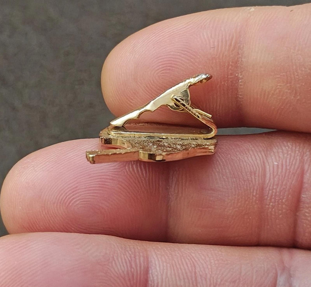 Gold-tone enamel tie clip side view with raised textured gold backing