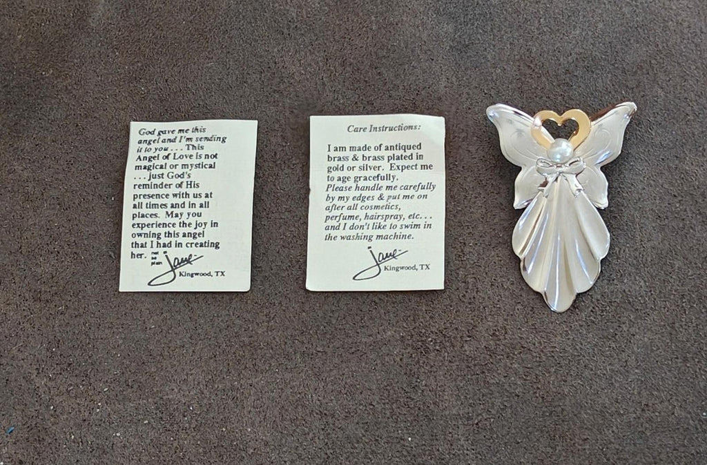 Angel pin with faux pearl and gold heart halo beside care instruction cards