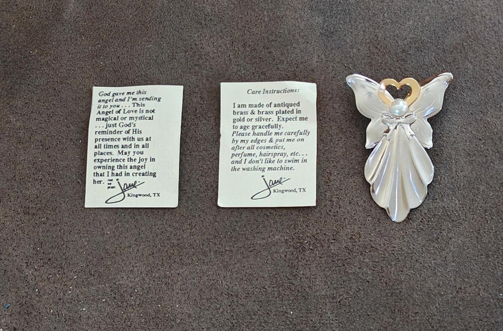 Angel pin with faux pearl and gold heart halo beside care instruction cards