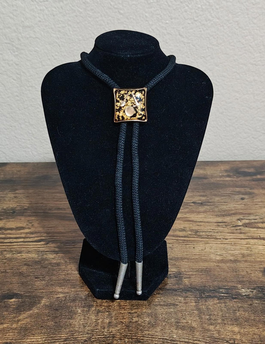 Black bolo tie on display bust, gold square pendant with gold flecks and miner details