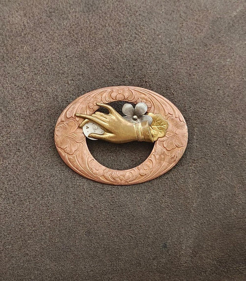 Round engraved bronze-toned brooch featuring a gold bird and gray floral centerpiece