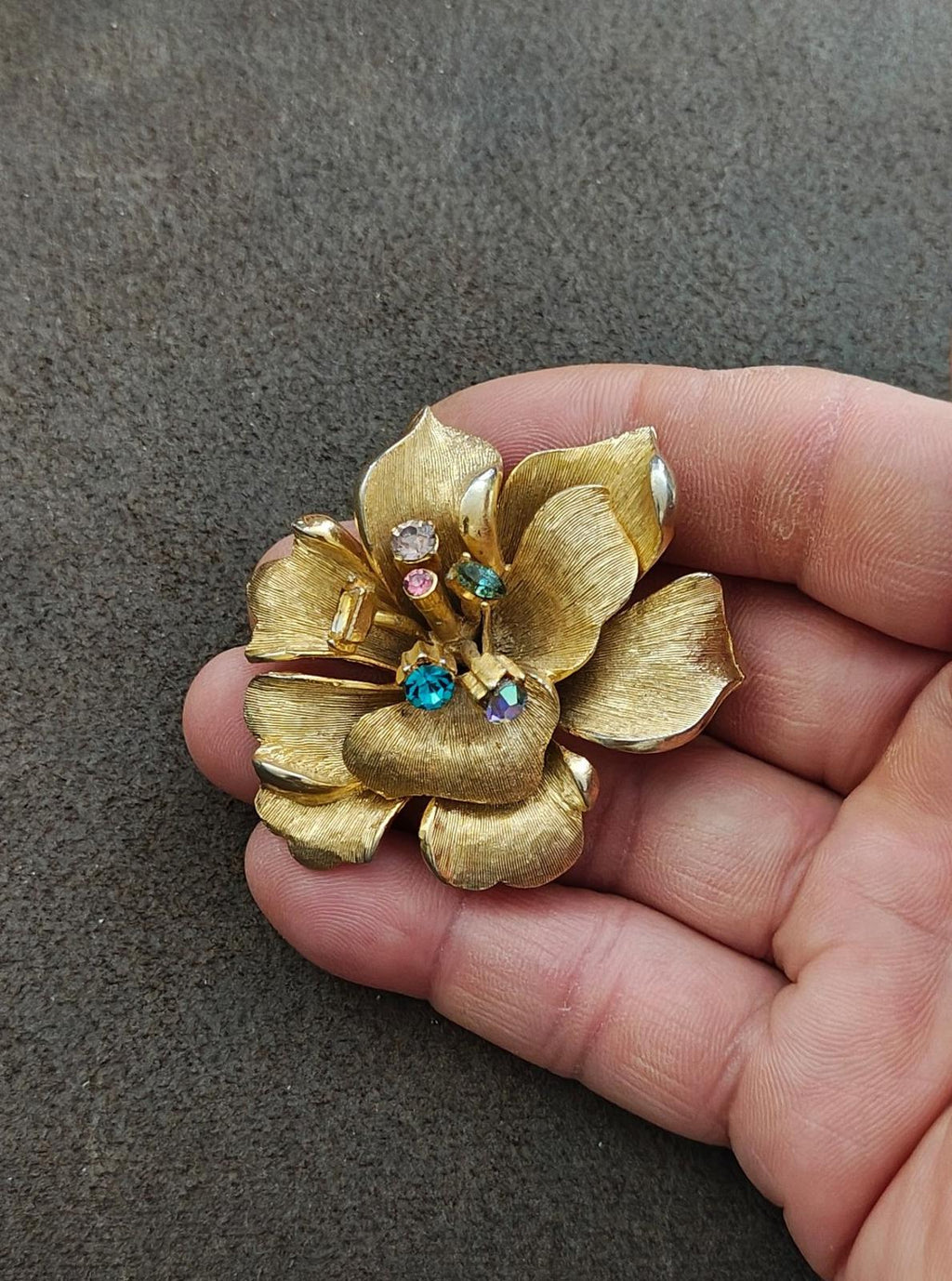 Gold-tone flower brooch with rhinestone cluster at the center