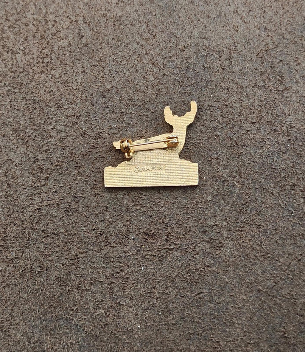 Gold-tone pin back with clasp and bar on a textured base plate