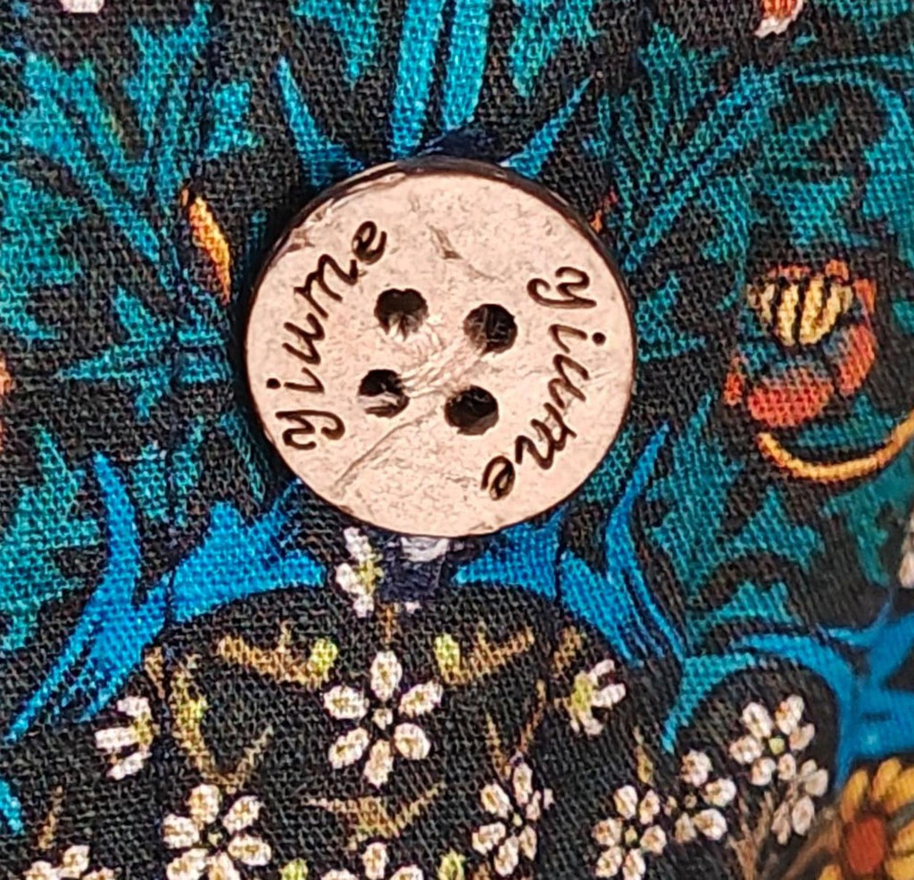 Blue floral Hawaiian shirt fabric with round button featuring script Yiume logo