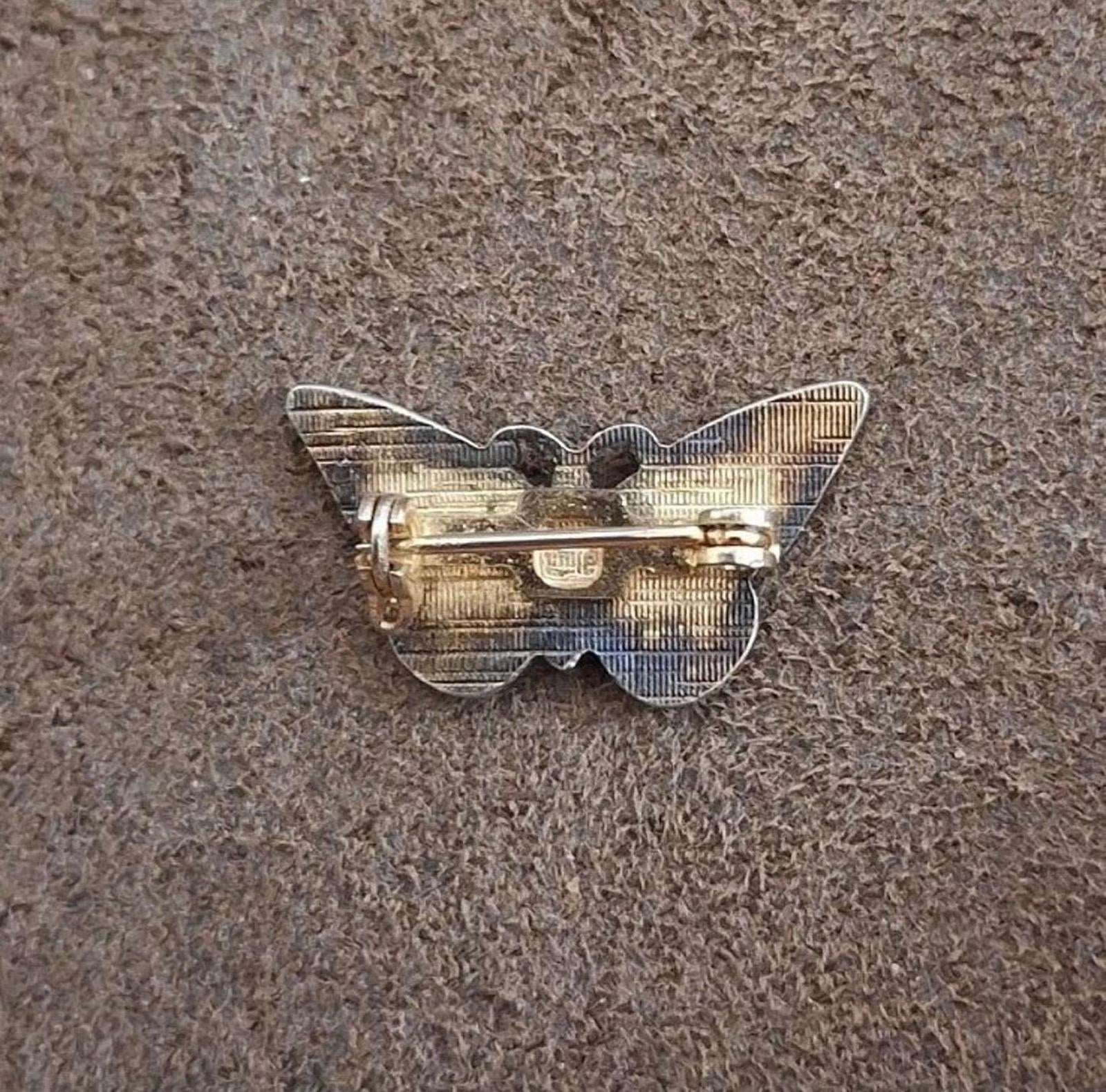 Enamel butterfly pin brooch back view with metal clasp and hinge mechanism.