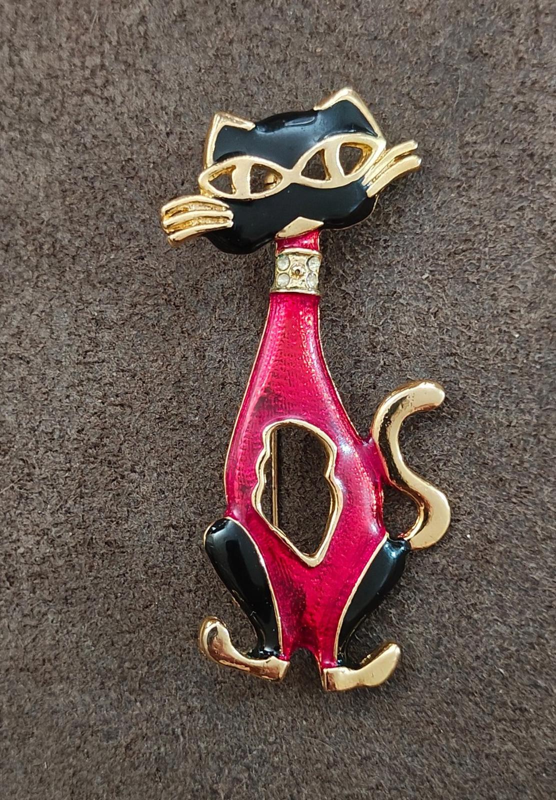 Red and black enamel cat mask brooch with gold-tone detailing, standing pose.