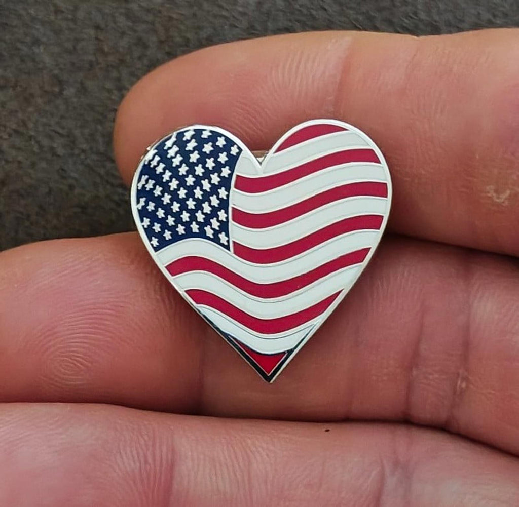 Heart-shaped enamel flag pin in hand, blue stars with red and white wavy stripes